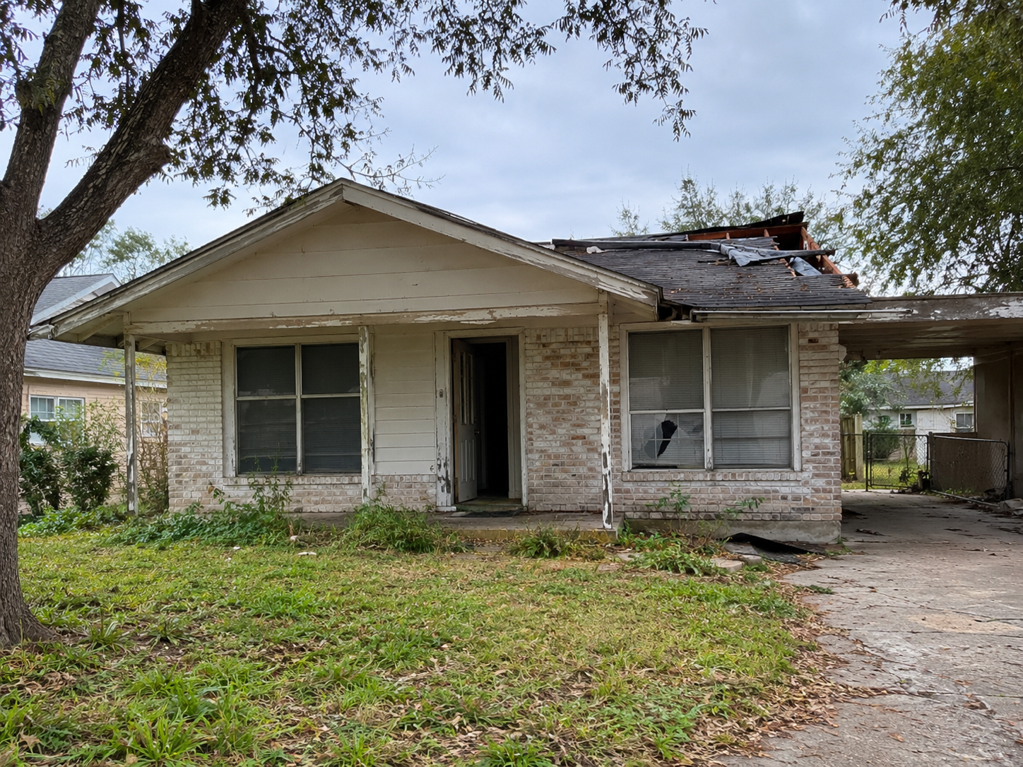Older house in need of repairs under a cloudy sky in San Benito, Texas